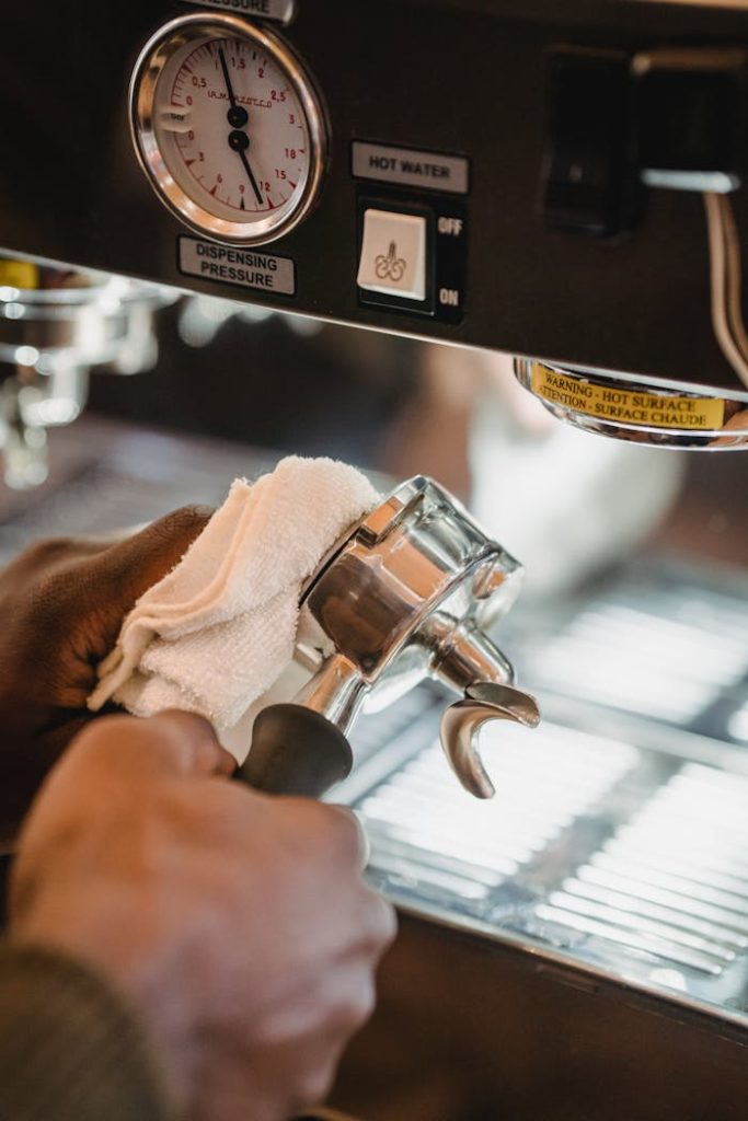 Close-up of a barista cleaning a portafilter on a coffee machine, ensuring hygiene.